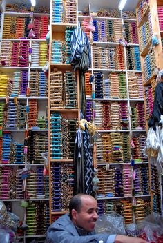 a man sitting in front of a wall full of colorful items