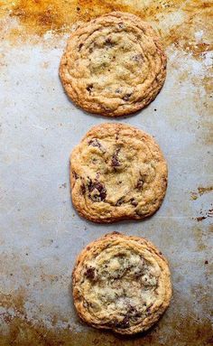 three chocolate chip cookies on a baking sheet