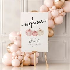 a welcome sign surrounded by balloons in front of a white wall with gold foil accents