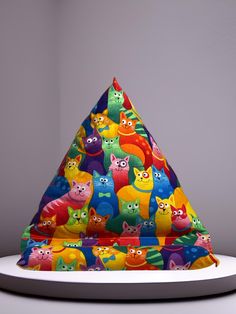 a multicolored triangle shaped hat with cats on it