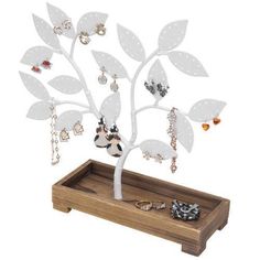 a white tree with jewelry hanging from it's branches on a wooden tray in front of a white background