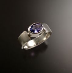 This 5.5 x 7.5 mm Tanzanite oval is bezel-set with tapered cold forged band. The stone is a natural medium dark purple-blue eye clean stone. It weighs about 1ct. Pictured ring is size 7. Specify your ring size in a note to seller at check-out. Modern Tanzanite Rings, Modern Oval Sapphire Promise Ring, Modern Oval Amethyst Ring With Polished Finish, Modern Oval Sapphire Ring With Tension Setting, Oval Sapphire Ring With Tension Setting As Gift, Modern Oval Sapphire Ring With Polished Finish, Modern Oval Tanzanite Ring, Modern Oval Tanzanite Sapphire Ring, Gift Sapphire Ring With Oval Tension Setting