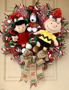 a christmas wreath with two stuffed toys hanging from it's side on a door