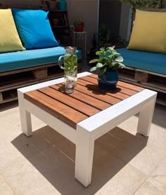 a wooden table sitting on top of a patio next to blue couches and pillows