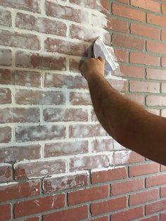 a man is painting a brick wall with white paint and a sponge roller on it