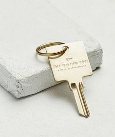 a gold keychain that says the giving keys on it sitting on a concrete block