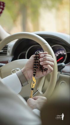 a person holding a rosary while driving a car