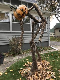 a fake spider with a pumpkin on it's head in front of a house