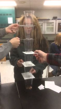 three people are around a blender that is being filled with liquid and placed on top of each other