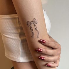 a woman's arm with a bow tattoo on the left side of her body