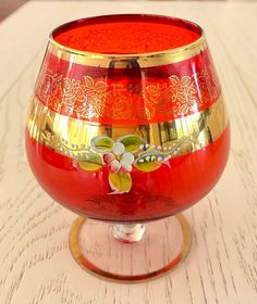 a red and gold vase sitting on top of a wooden table