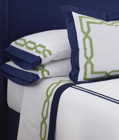 a bed with blue and white sheets and pillows