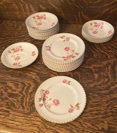 a bunch of plates that are sitting on a wooden counter top with flowers painted on them