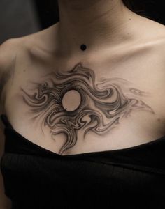 a woman's chest with an artistic tattoo design on her left shoulder and the sun in the center