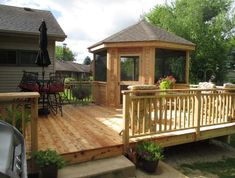 a wooden deck with a gazebo in the back ground and patio furniture on it