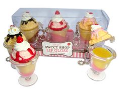 there are four ice cream sundaes in the glass cupcake display case,