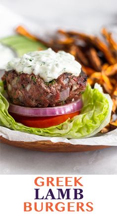 a burger with lettuce, tomato and onion on it sitting next to french fries