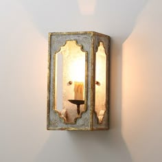 a wall light that is on the side of a wall with a candle in it