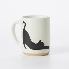 a white coffee mug with a black cat on it's side and a brown bottom