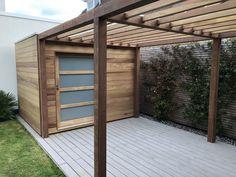 a wooden structure with a door on top of it next to a grass covered yard