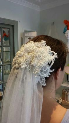 the back of a bride's head wearing a veil with flowers on it,