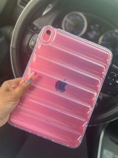 a woman holding an iphone case in her hand while sitting in the drivers seat of a car