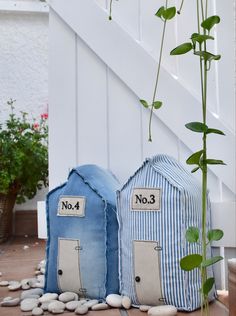 two small blue and white houses sitting next to each other on top of rocks in front of a stair case