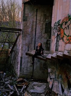 a woman sitting on a ledge in an abandoned building