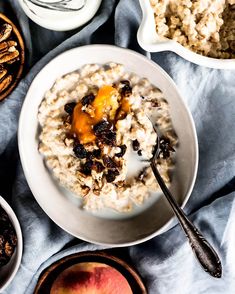 bowl of oatmeal with fruit and nuts next to bowls of other breakfast foods