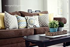 a living room with brown couches and pillows on top of the couch is shown