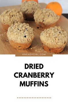 some muffins are on a cutting board with oranges in the background