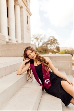 a beautiful young woman sitting on the steps in front of a building wearing a black dress