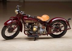 an old fashioned motorcycle is parked in a garage with tile flooring and tan walls