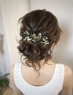 the back of a woman's head wearing a white top with flowers in her hair