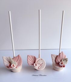 three little pink vases sitting on top of a white table next to each other