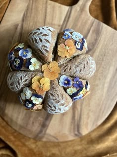 a wooden cutting board topped with buns covered in blue and yellow flowers on top of it