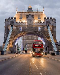 a red double decker bus driving under a bridge