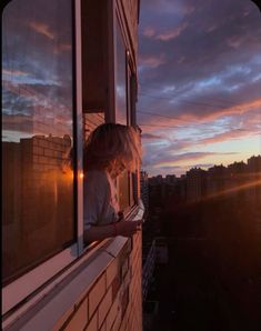 a woman is looking out the window at the sunset