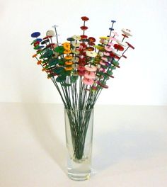 a vase filled with lots of different colored pins and needles on top of a white table