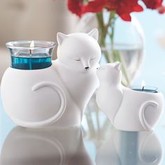 a white cat and kitten figurine sitting next to each other on a table