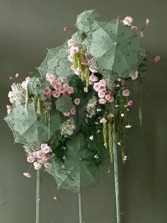 several green umbrellas with pink flowers on them in front of a gray wall and floor