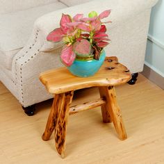 a small wooden stool with a potted plant on it in front of a couch