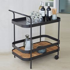 a bar cart with bottles and glasses on it sitting next to a wine glass holder