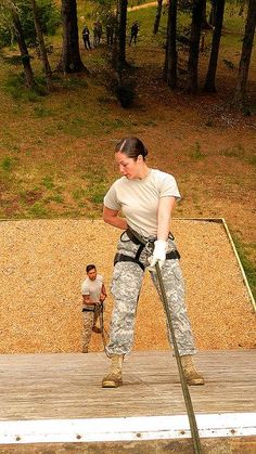 a woman is standing on a wooden platform with a pole in her hand and another person behind her