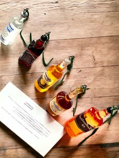 three bottles of alcohol sitting on top of a wooden table next to an open note