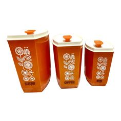 three orange containers with white designs on them