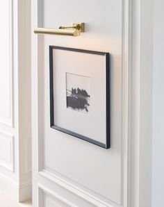 a black and white photo hanging on the wall next to a framed photograph with a gold handle