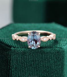 an engagement ring with a blue topazte surrounded by white diamonds on a green velvet box