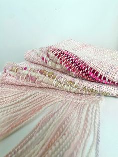 three pieces of pink and white woven material on top of each other, one folded over the other