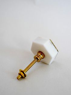 a close up of a white knob with a gold colored screw on the top and bottom